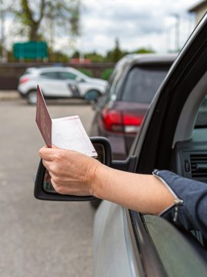 women hand through car window giving passport for customs control, driver with an identity card in a car at a border checkpoint